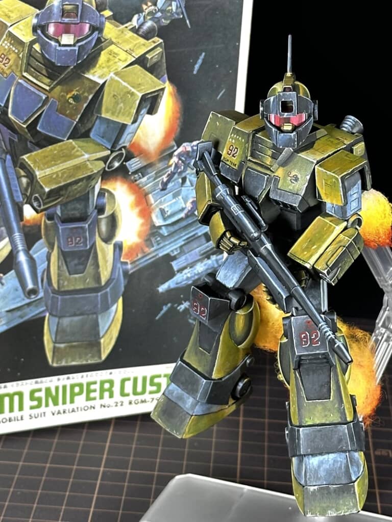 パッケージの横に立つジムスナイパーカスタムのガンプラ