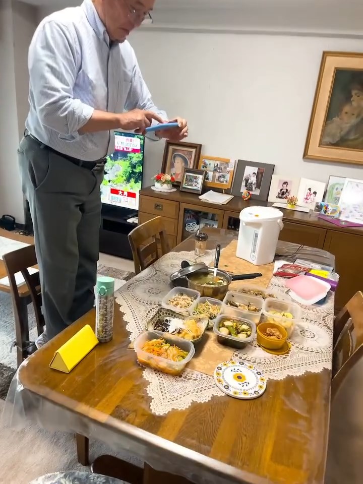 娘の料理を引きで撮って収めようと奮闘するお父さん。くれぐれも足元には気を付けて……！