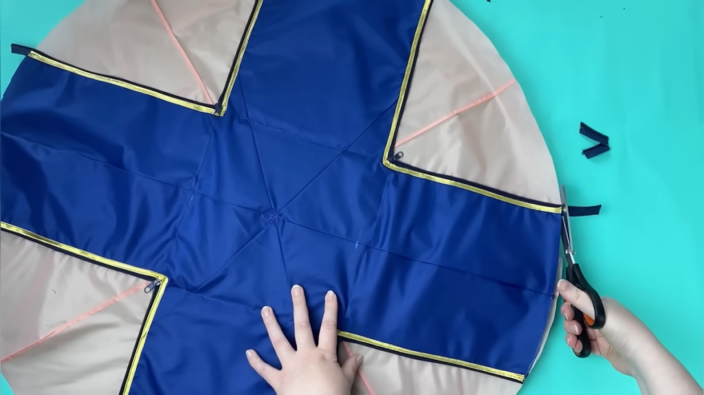 青い生地は十字型にカットして、金色のパイピングとファスナーを施します。