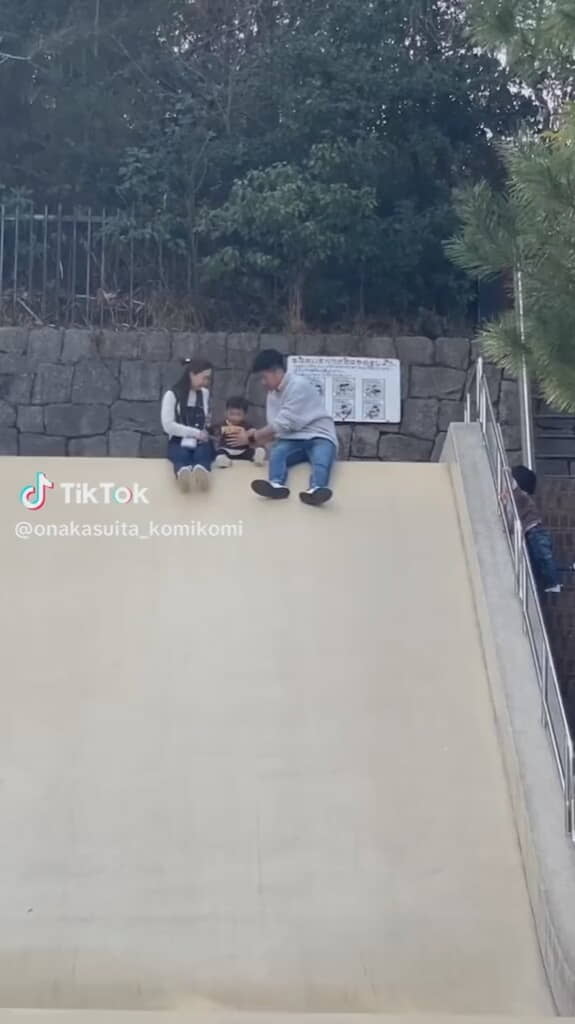 大きな滑り台をすべる3人の親子