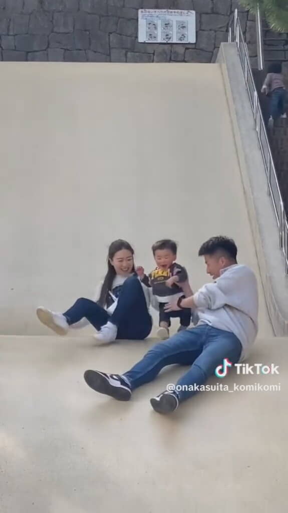 大きな滑り台をすべる3人の親子