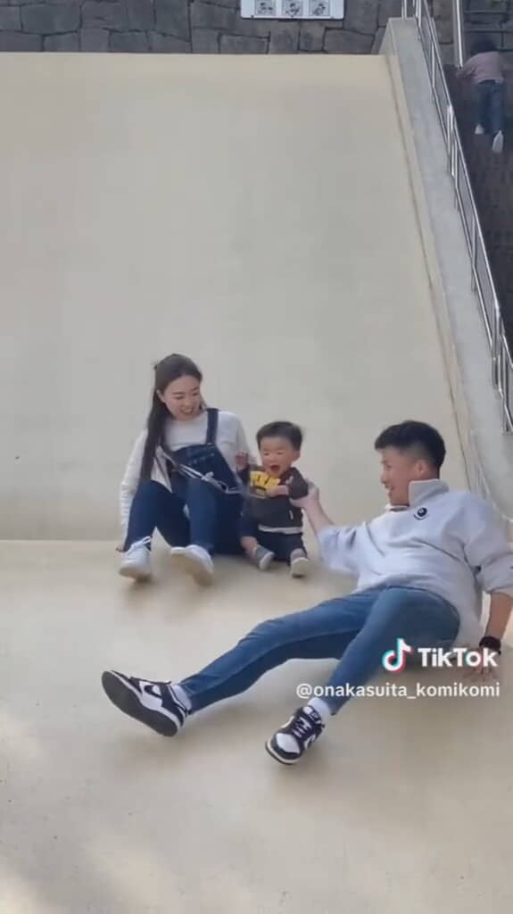 大きな滑り台をすべる3人の親子