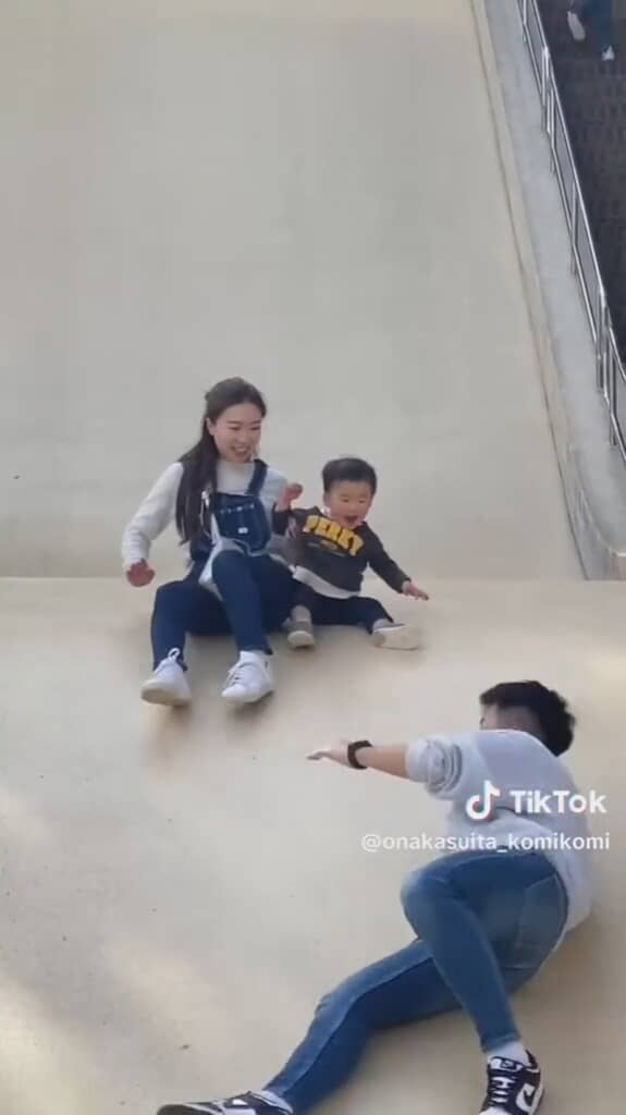 大きな滑り台をすべる3人の親子