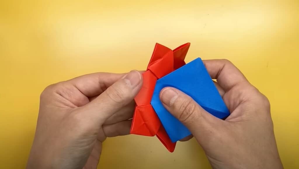 青い折り紙（小）で顔を作ってはめ込みます