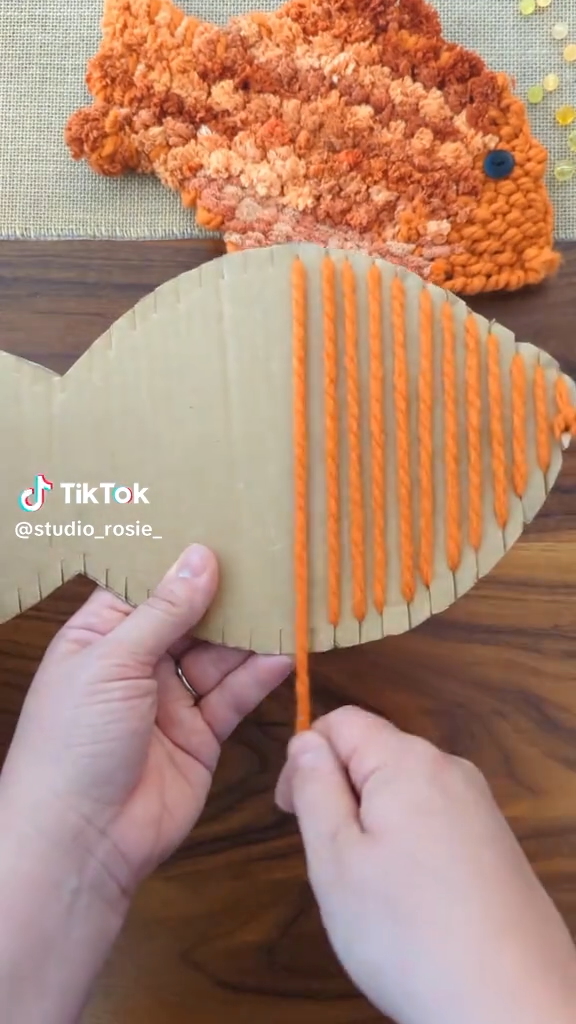 金魚型の段ボールに毛糸を巻き付けていく
