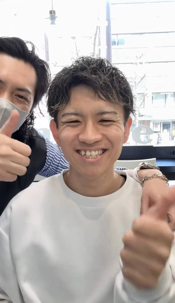 髪を切ってもらった男性が笑顔でグーサインをしている