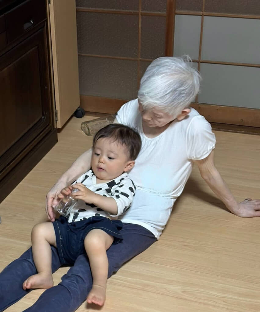 大好きなひいばあちゃんの膝で御満悦。苦しゅうない（？）