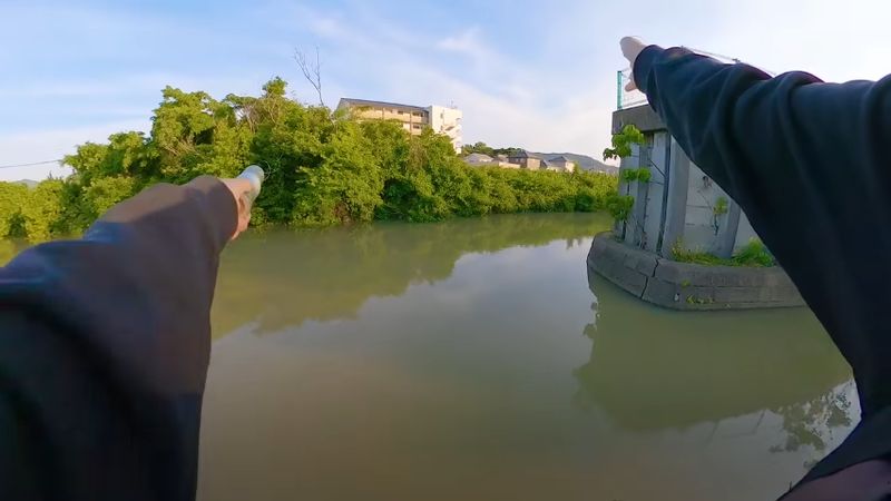 ミミズが付いた釣り針を川へ投げ入れる