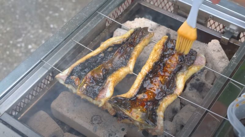 さばいたウナギにタレを塗る