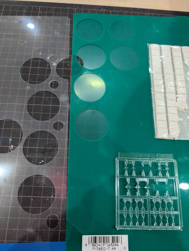 2色のクリアファイルを円形に切って接着し塗装。H・アイズ（右下）でディテールを追加し、ひっつき虫（右上）で本体に取り付ける