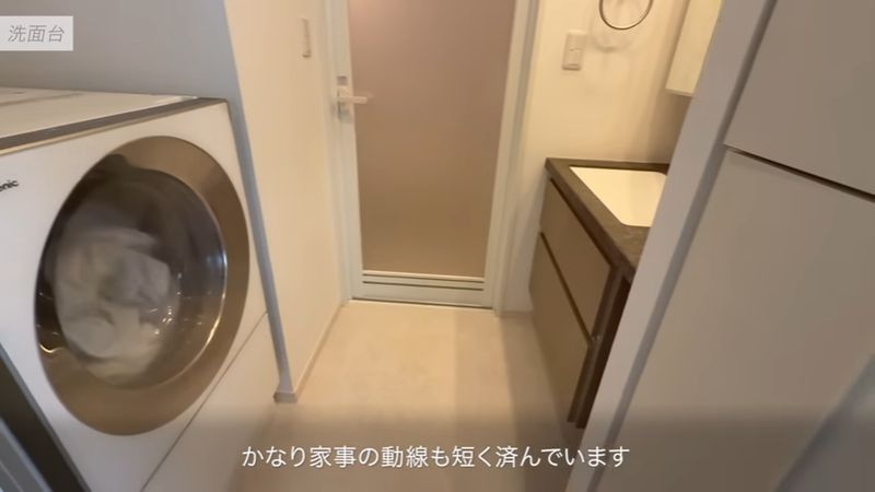 左側に洗濯機、右側に服用の収納棚がある洗面所