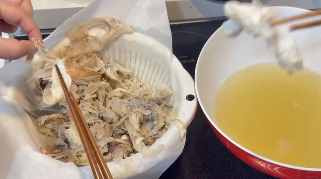 黄金色の出汁を取った後のアラの身をつまむ
