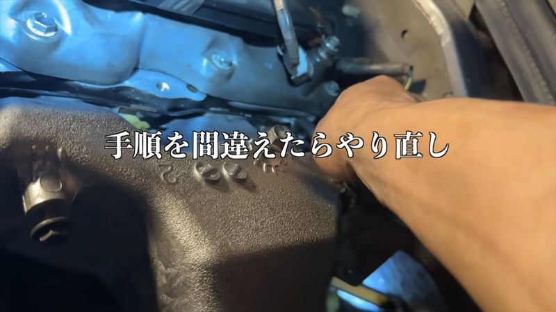見えないところに手を突っ込んでエンジン部品を固定する