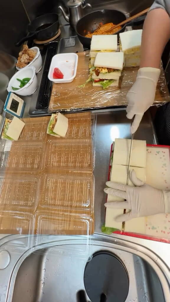 サンドイッチを半分にカットして容器に詰めていく