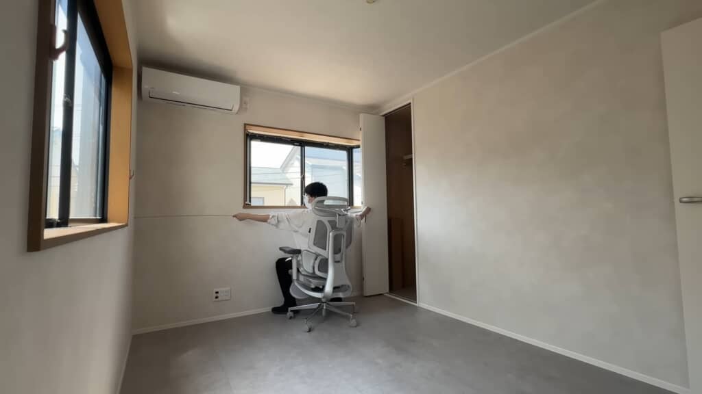 壁一面の寸法を測っている男性の背面