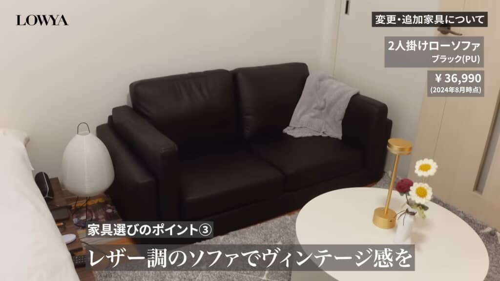 黒いレザー調ソファと白いローテーブルを写した室内。