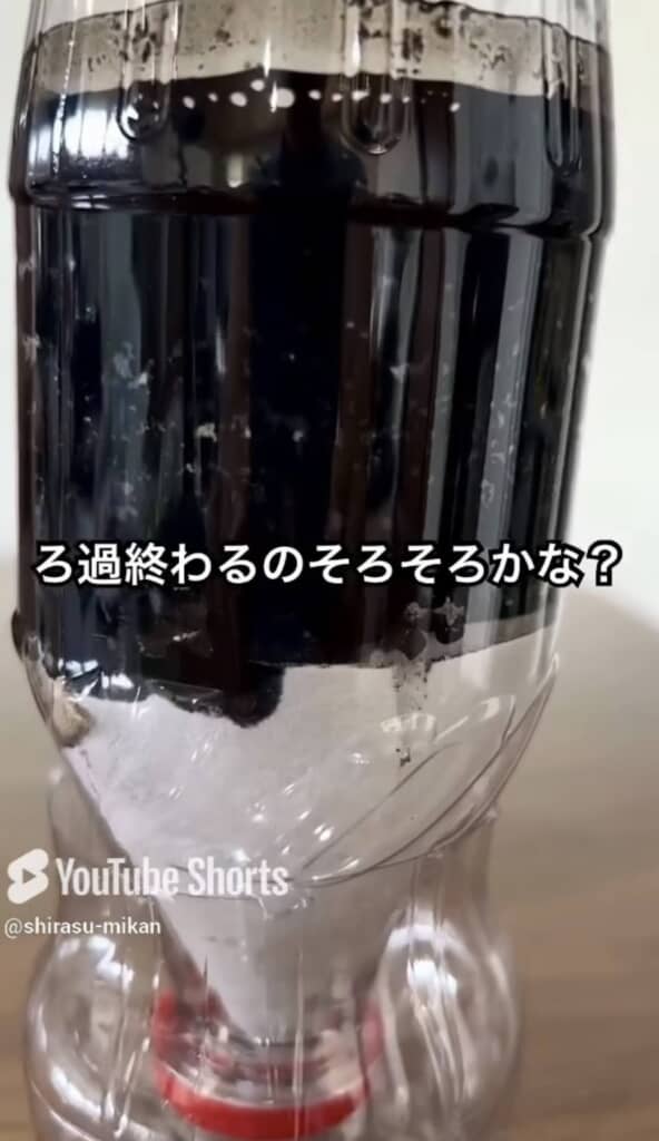 ペットボトルで作られた自作ろ過装置に黒い液体が溜まりつつある様子