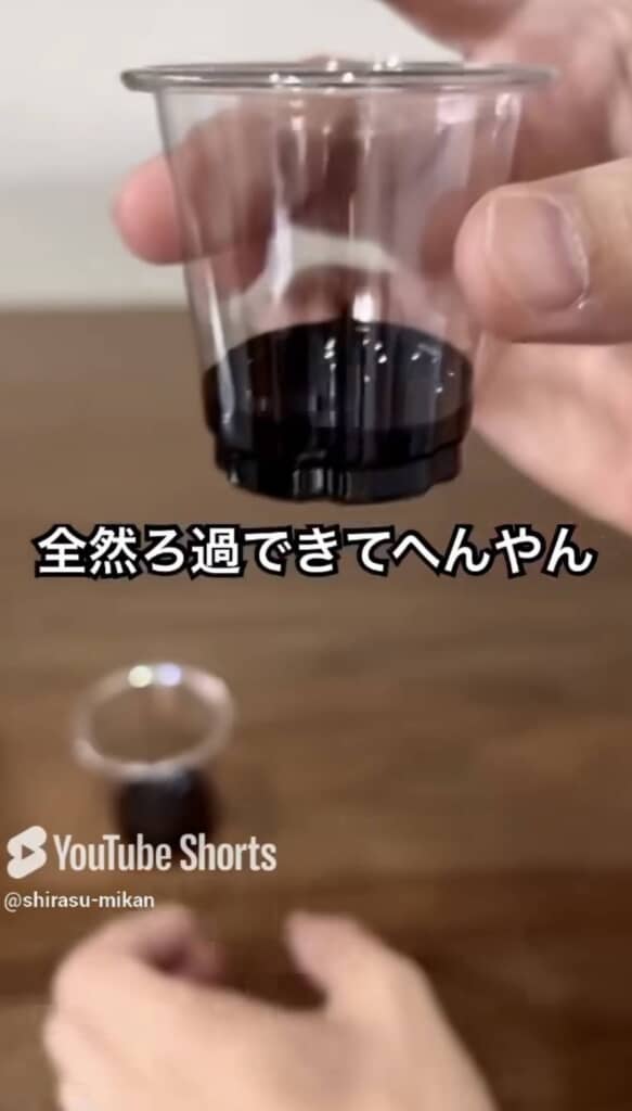 透明なカップに黒い液体が入っているのを手に持つ様子