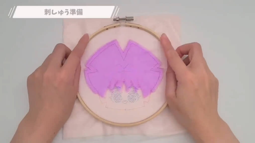 肌の生地、前髪パーツ、刺繍シートの順に重ねて刺しゅう枠で挟みます