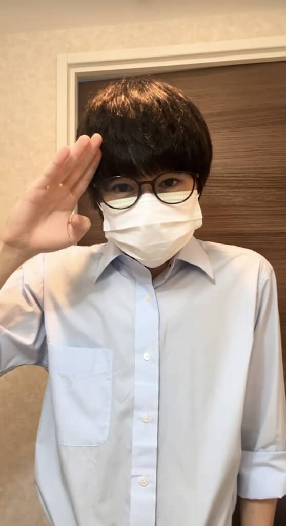 黒髪の男性がマスクをして敬礼している