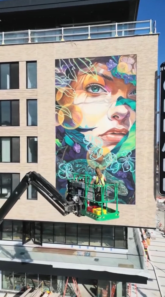 リフトに乗って制作された、みどりが基調の人物の壁画