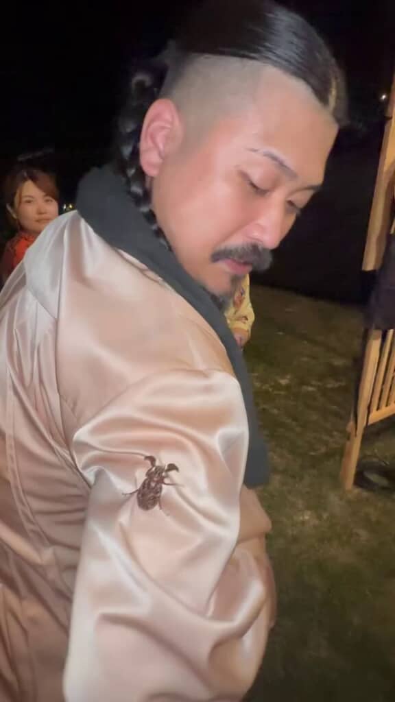 バンドマンの肩に乗っている茶色い虫