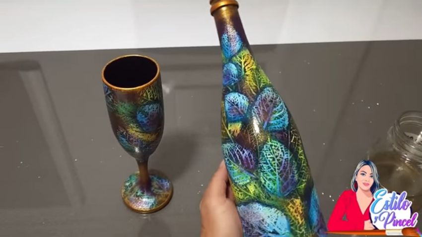 緑と黄緑、空色の葉が描かれたワインボトルとグラス