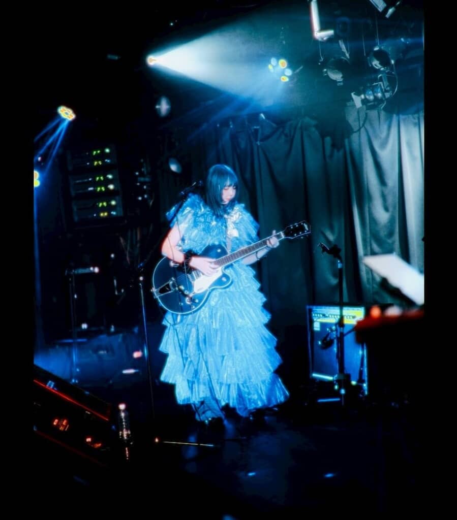 シンガーソングライターとしてステージに立ち、ギターを弾くナナジュウハチさん