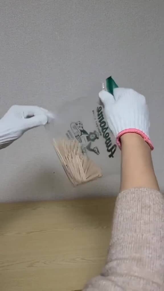 爪楊枝を入れた袋を斜めにして振っているところ