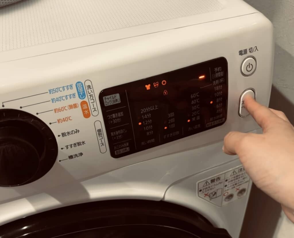 洗濯機のスタートボタンを押している様子