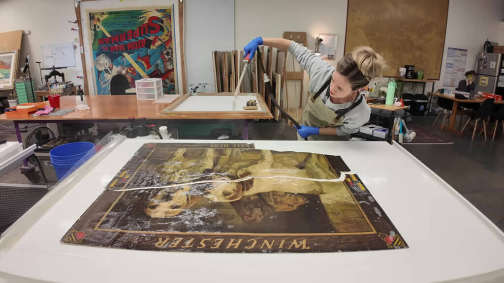 ポスター全体に霧吹きをかけ、平らにしている場面