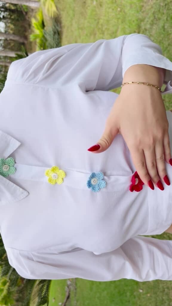 かぎ編みされた花のモチーフをつけたシャツを着用