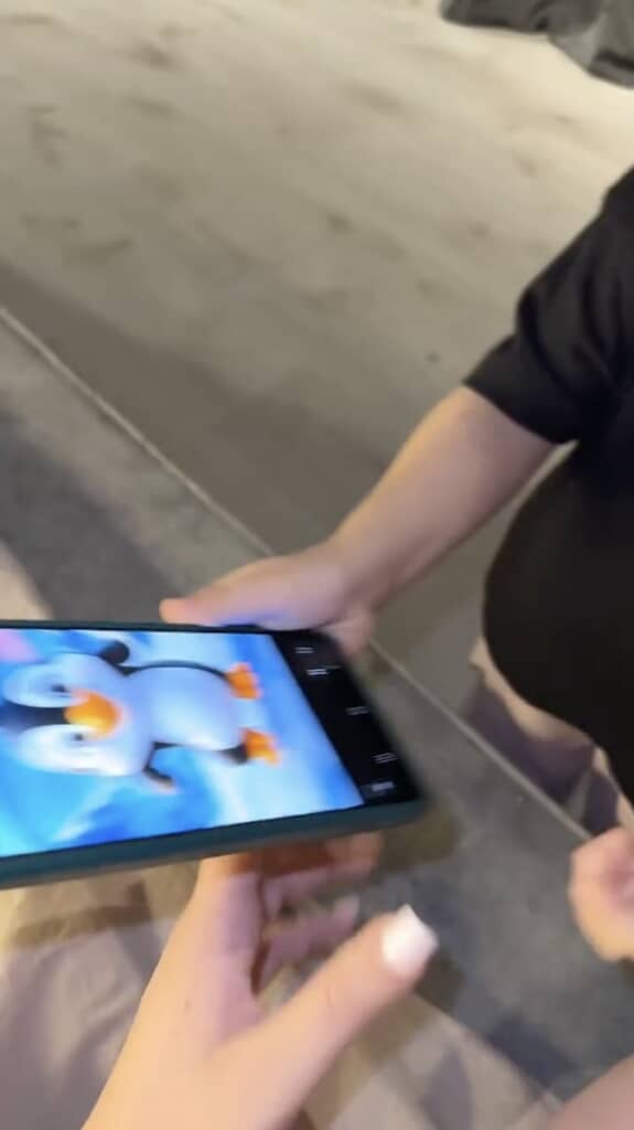 ペンギンが踊るアニメが表示されたスマホをママに渡す娘さん