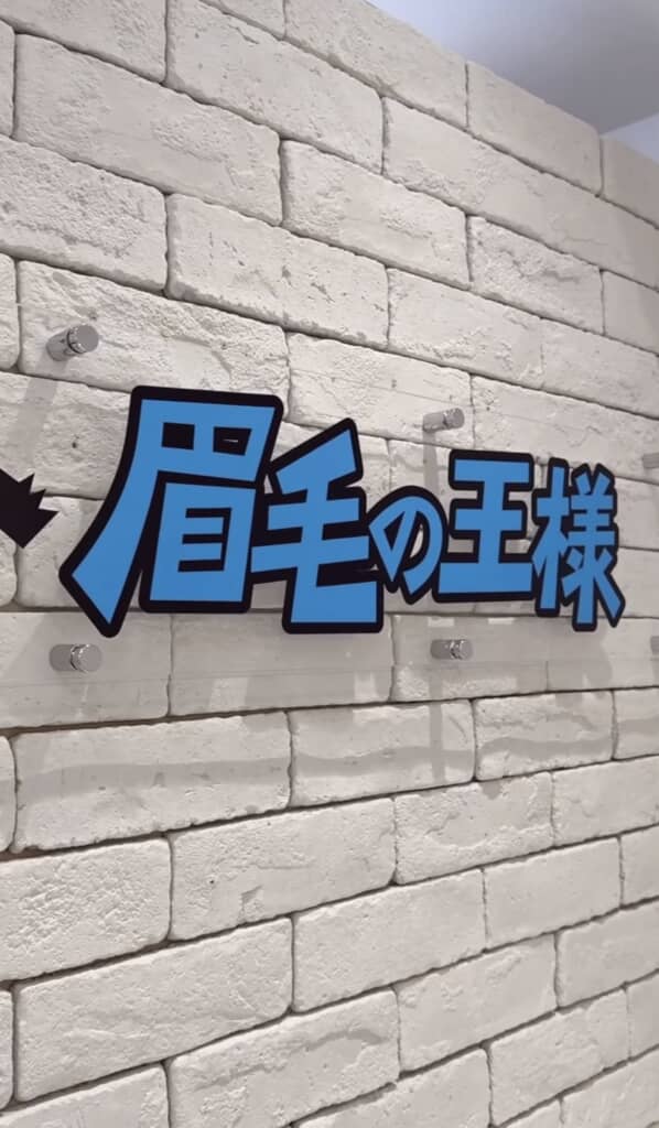 白いレンガ壁に掲げられた「眉毛の王様」の看板