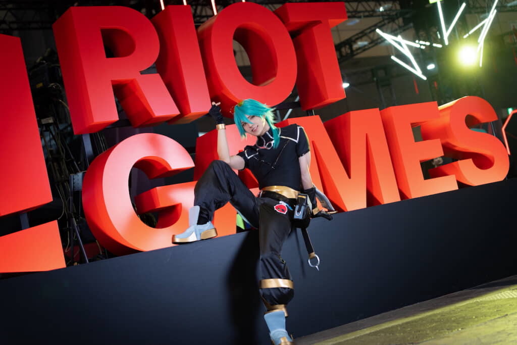 RIOT GAMESの大きなロゴの前でポーズ