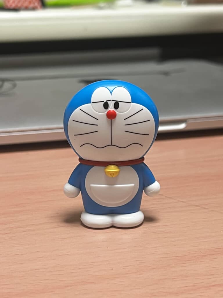 少し悲しそうな表情のドラえもんフィギュアが机の上に立っている正面の様子