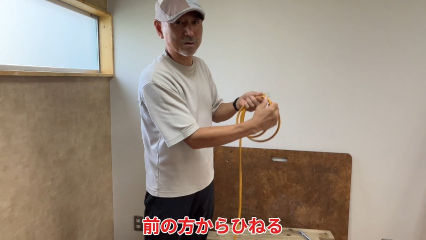 右手をひねり、前方から回り込むような動作で左手にコードを渡す