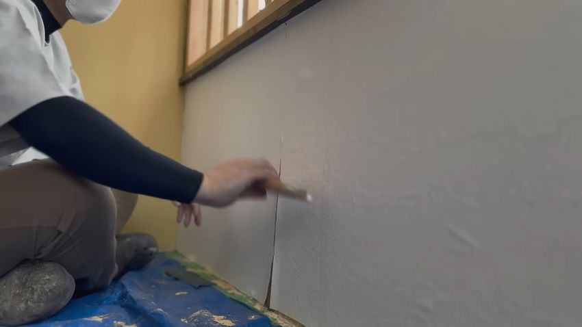 窓側の壁に白い壁紙を貼る様子