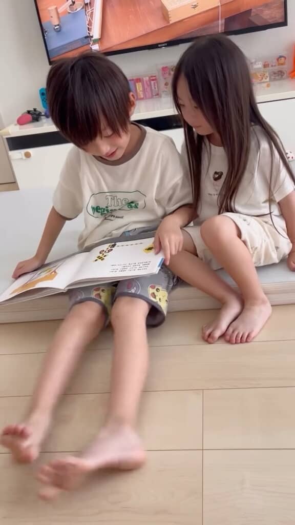 こよちゃんに絵本を読み聞かせてあげるあさくん
