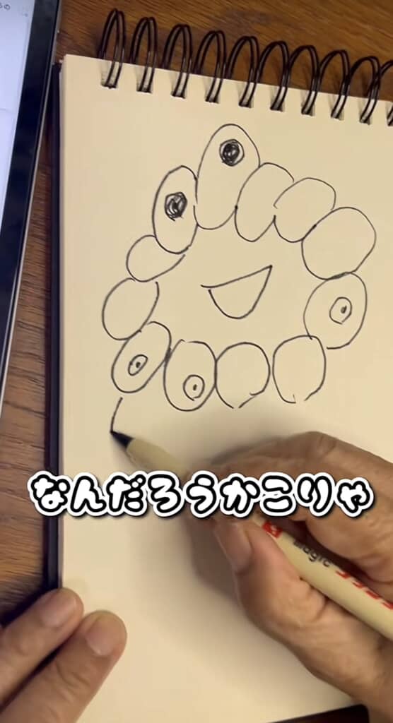 目のある楕円が並び、中央に笑顔の口が描かれた顔のようなスケッチ。