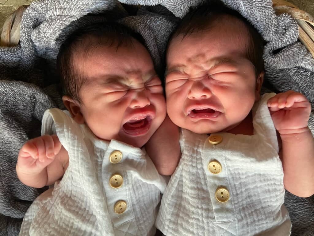 顔をぴったり寄せ合いながら、そっくりな表情で泣いている赤ちゃん時代の双子ちゃん
