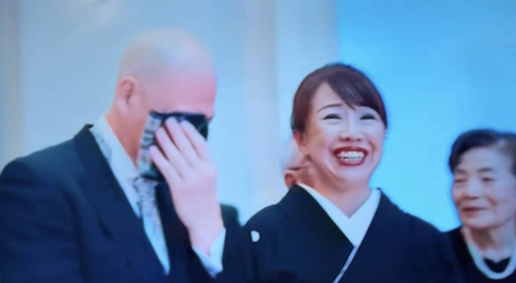 感極まり涙を拭う父親と笑顔の母親が並ぶシーン。