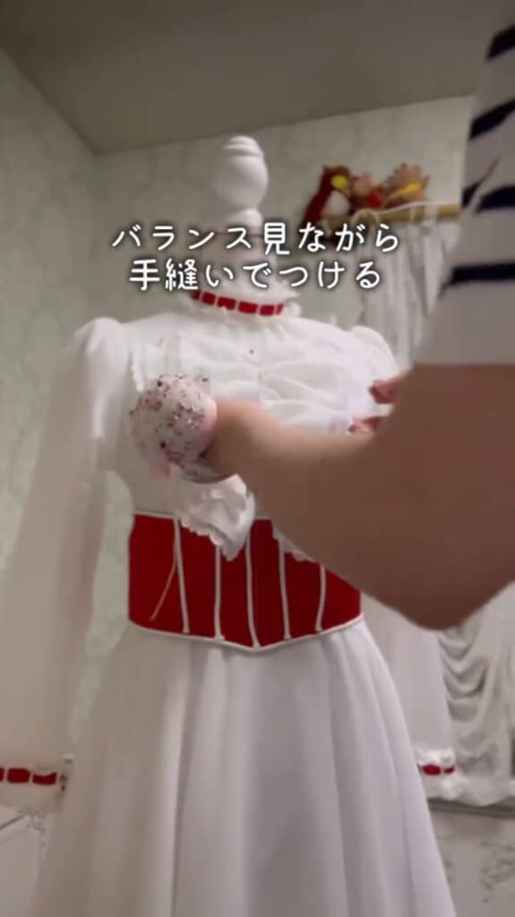 手作りの胸元の飾りを手縫いで取り付ける様子