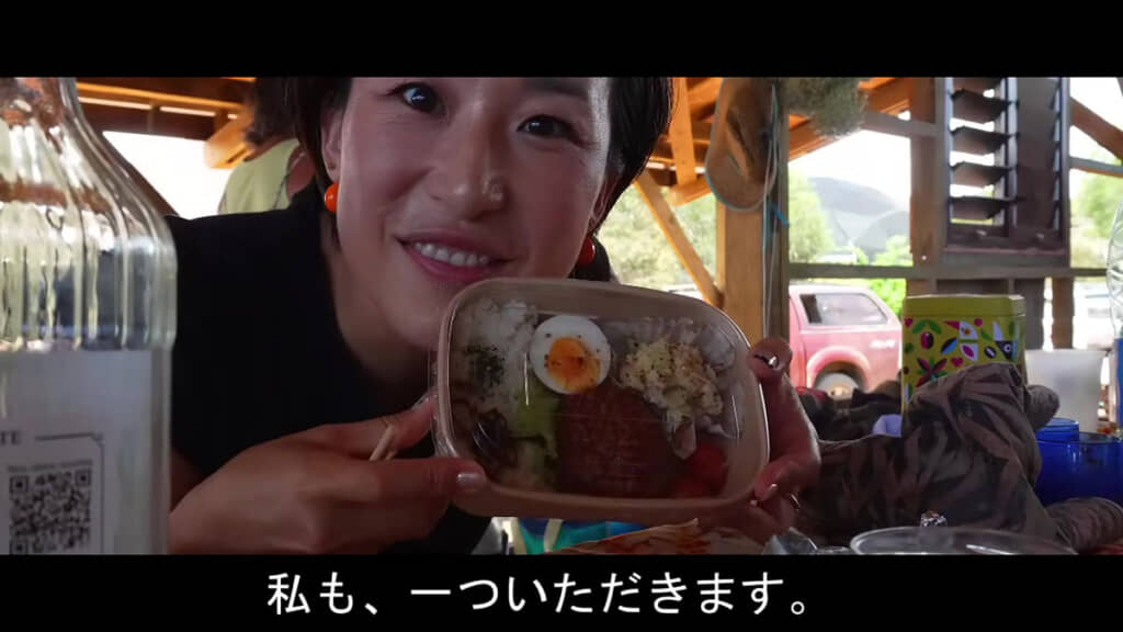 ヒロ子さんが弁当箱を持って微笑んでいる