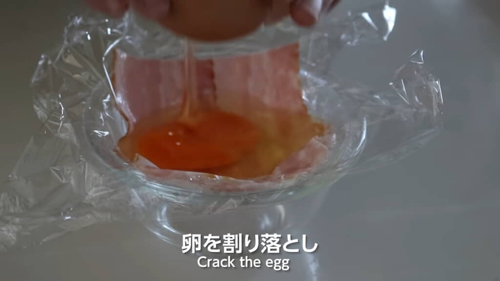 ベーコンの上に卵を割り落とす