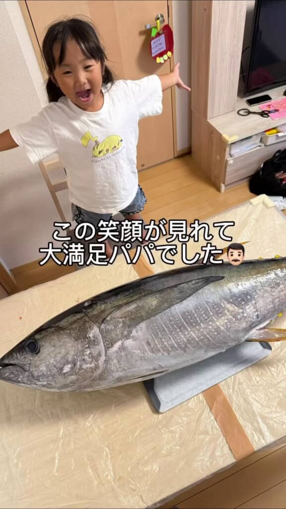 マグロを前に両手を広げて喜ぶ娘