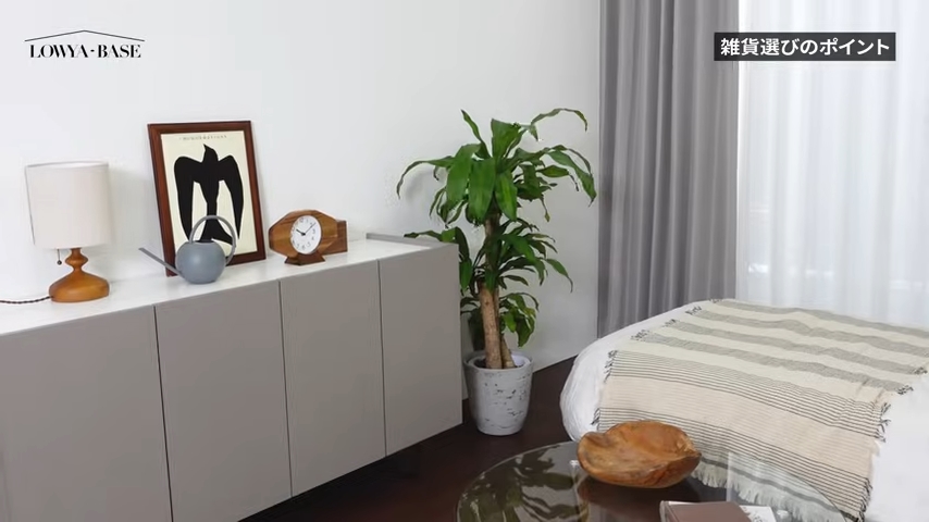 サイドボードの上には、ダークブラウンの額縁に入ったモノクロのアートやナチュラルな時計、グレーのじょうろ、間接照明を置いている