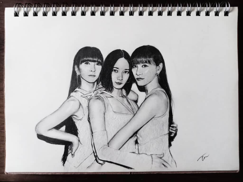 スケッチブックに描かれたPerfumeのリアルな鉛筆画ポートレート。