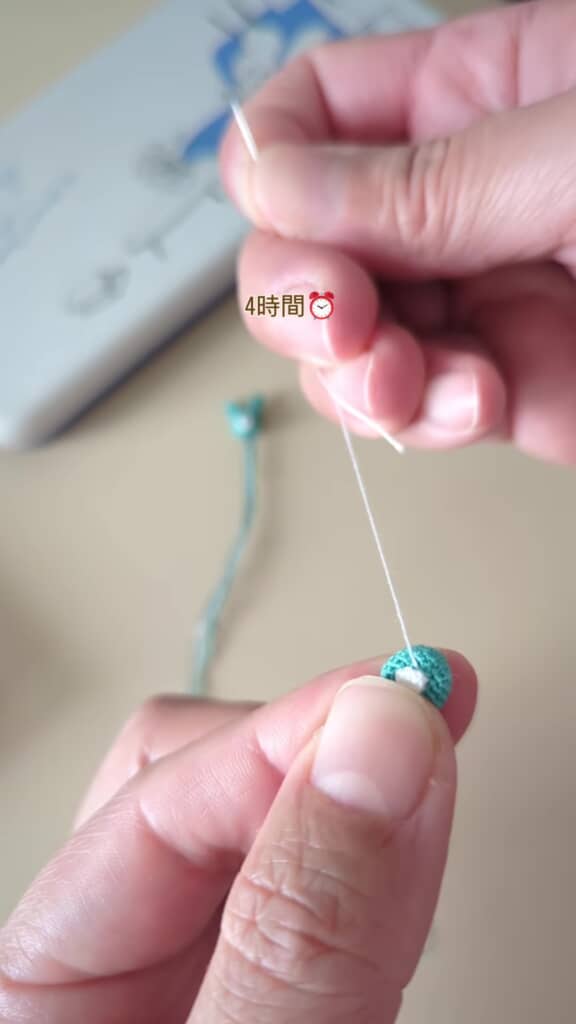 青いぬいぐるみに白い鼻を刺しゅうしている場面