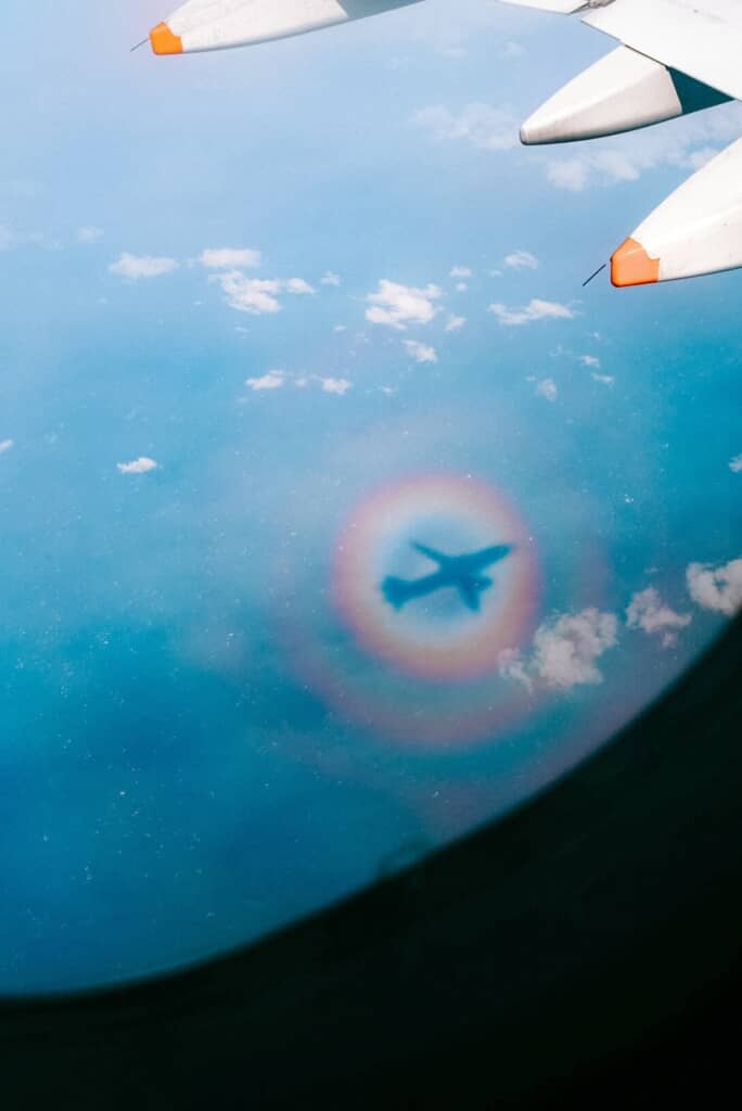 円環状の虹色の光をまとっている飛行機の影